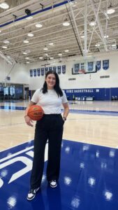 Jaelyn Arndt standing on a basketball court smiling at the camera. 